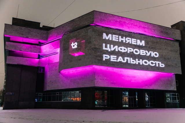 Надпись «Меняем цифровую реальность» на фасаде с розовой подсветкой