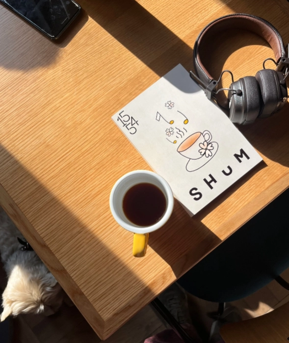 Кофе, наушники и карточка SHUM на деревянном столе