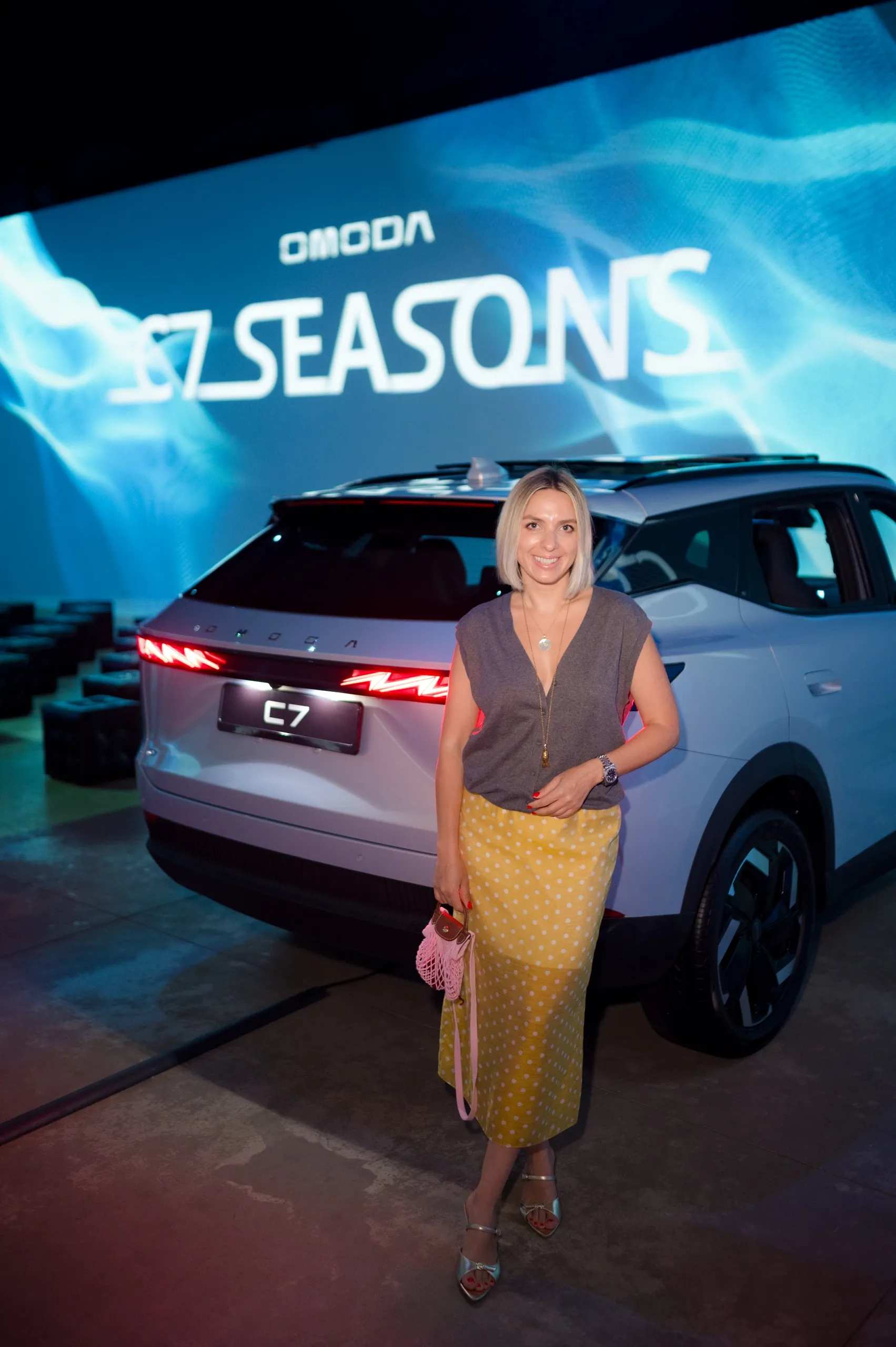 Гостья позирует рядом с автомобилем OMODA C7