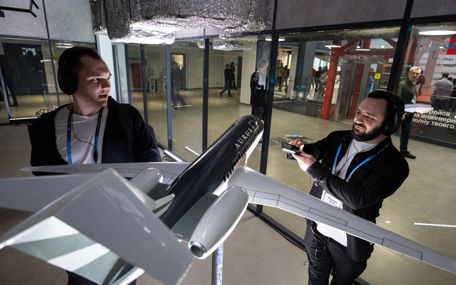Два посетителя изучают технический объект на выставке